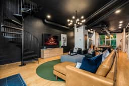 Enjoy the living room's 65" tv from the comfort of the leather couch and chairs. The living room is located adjacent to the full kitchen. The spiral stair case is one of two ways to reach the 3rd floor