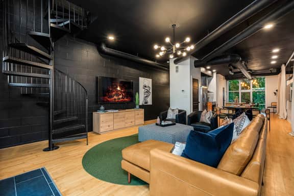 Enjoy the living room's 65" tv from the comfort of the leather couch and chairs. The living room is located adjacent to the full kitchen. The spiral stair case is one of two ways to reach the 3rd floor